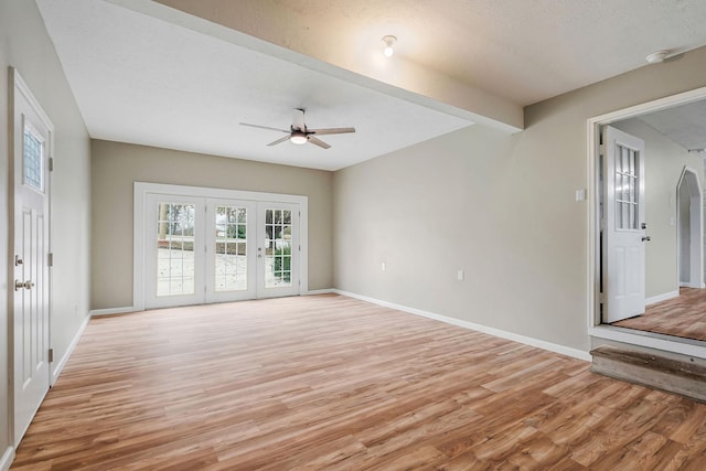 unfurnished living room with beamed ceiling, ceiling fan, a textured ceiling, and light wood-type flooring