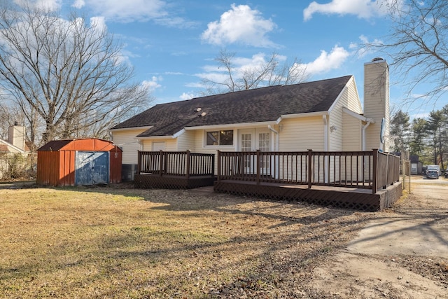 back of house with a yard, a deck, and a shed