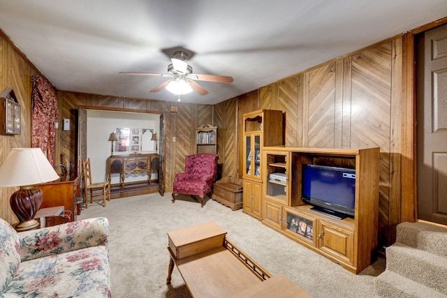 living room featuring wooden walls, ceiling fan, and carpet