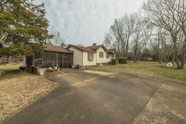 view of home's exterior with a sunroom and a yard