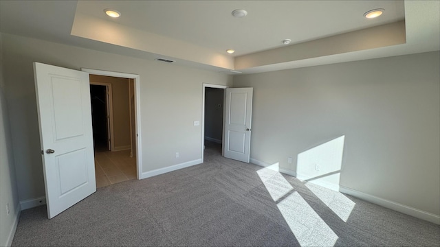 unfurnished bedroom featuring a raised ceiling and carpet floors