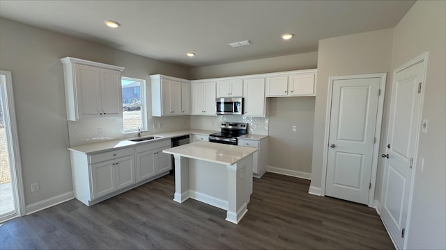 kitchen featuring sink, a kitchen island, white cabinets, and appliances with stainless steel finishes