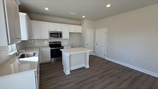 kitchen with dark wood-type flooring, sink, white cabinetry, appliances with stainless steel finishes, and a kitchen island