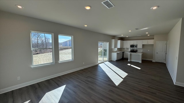 kitchen with white cabinetry, appliances with stainless steel finishes, dark hardwood / wood-style flooring, and a center island