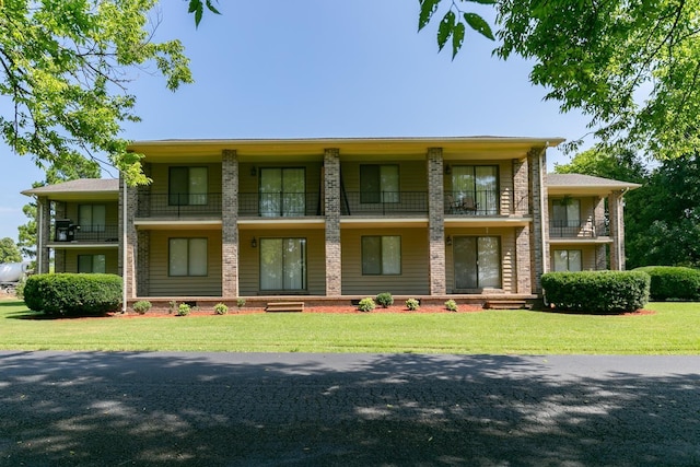 view of front of property with a balcony and a front lawn