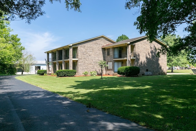 view of side of property featuring a lawn and a balcony