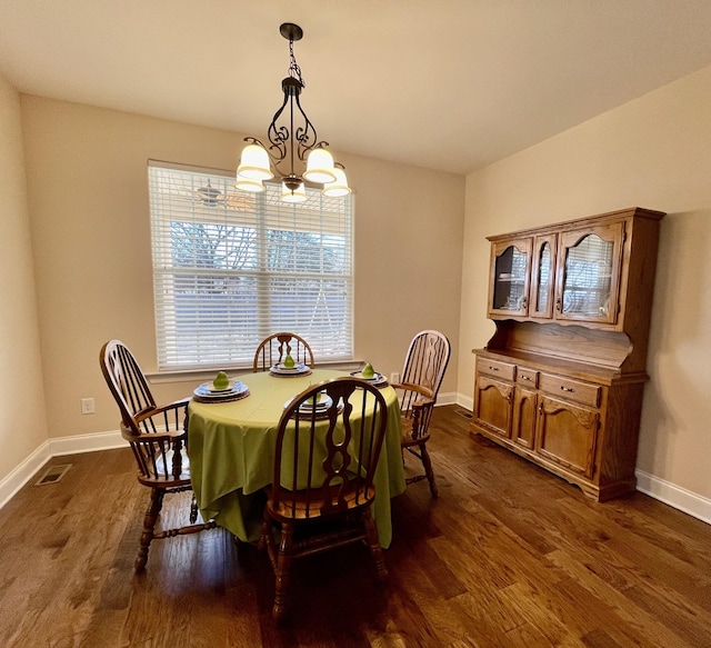 dining space with dark hardwood / wood-style floors and an inviting chandelier