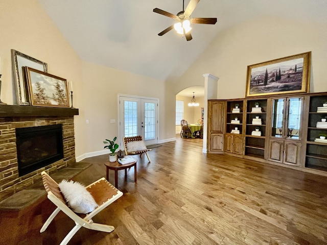 living room with wood finished floors, plenty of natural light, a fireplace, arched walkways, and french doors