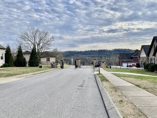 view of street with sidewalks, curbs, a gated entry, and a gate