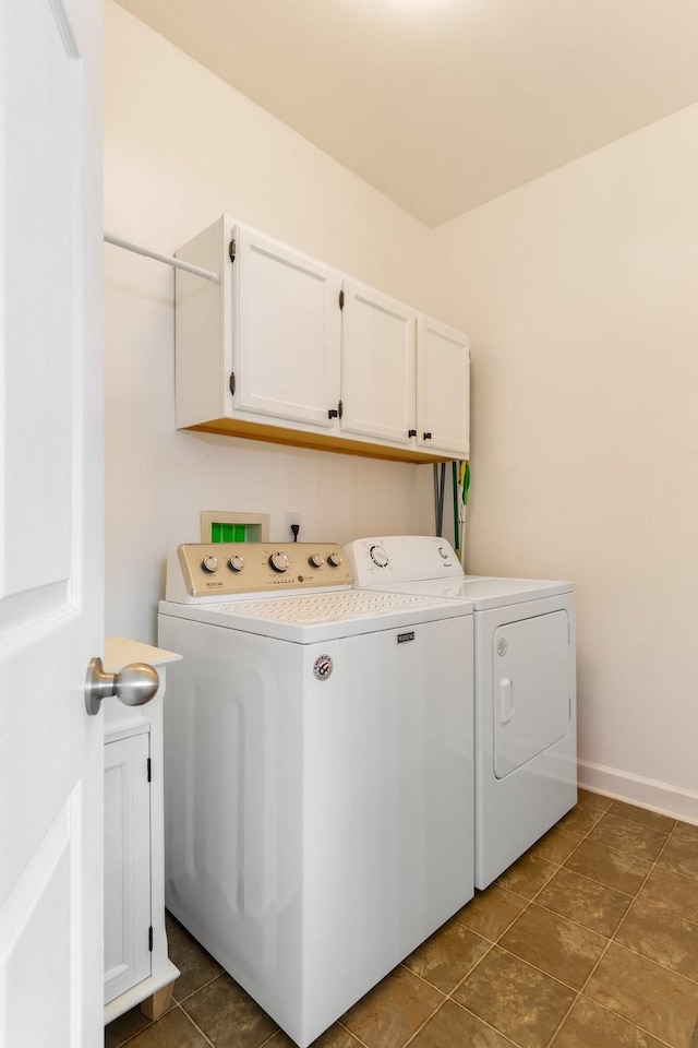 laundry room featuring cabinets, washing machine and dryer, and dark tile patterned floors