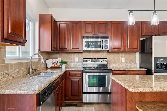 kitchen featuring appliances with stainless steel finishes, light stone countertops, sink, and hanging light fixtures