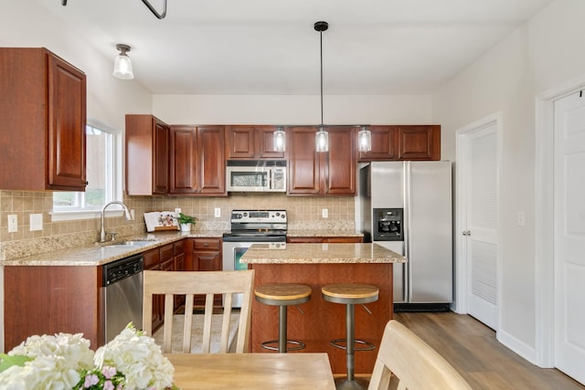 kitchen with dark wood-type flooring, sink, tasteful backsplash, hanging light fixtures, and stainless steel appliances