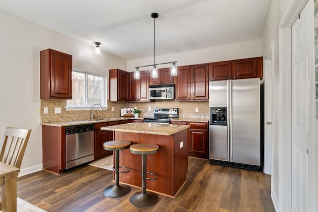 kitchen with dark hardwood / wood-style flooring, decorative light fixtures, a kitchen island, and appliances with stainless steel finishes