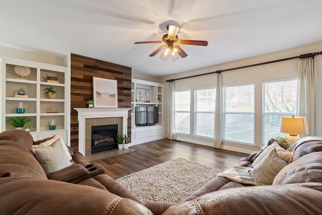 living room featuring dark wood-type flooring, ceiling fan, plenty of natural light, and a tile fireplace