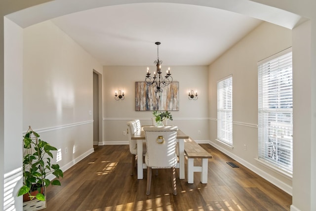 dining space with dark hardwood / wood-style floors and a chandelier