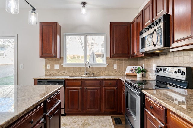 kitchen featuring appliances with stainless steel finishes, pendant lighting, sink, backsplash, and light stone countertops