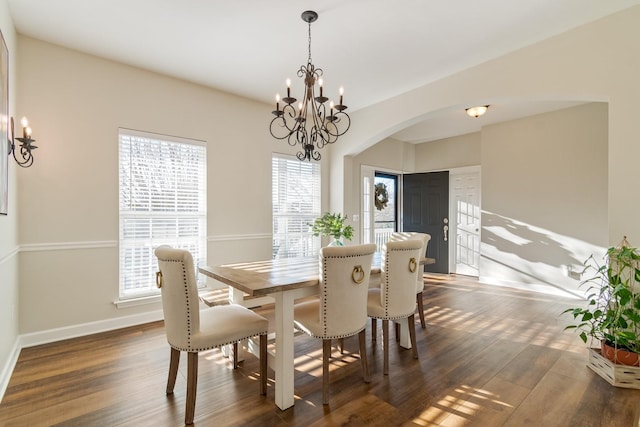 dining room with plenty of natural light, dark hardwood / wood-style floors, and an inviting chandelier