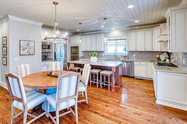 dining room featuring crown molding, sink, light hardwood / wood-style flooring, and a notable chandelier