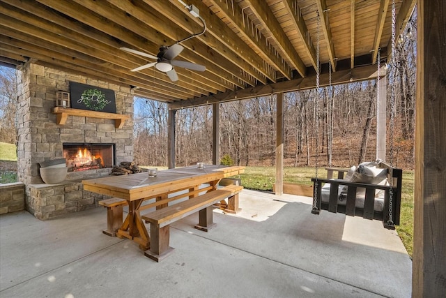 sunroom featuring ceiling fan and an outdoor stone fireplace