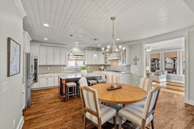 dining space with a notable chandelier, wood-type flooring, ornamental molding, and wooden ceiling