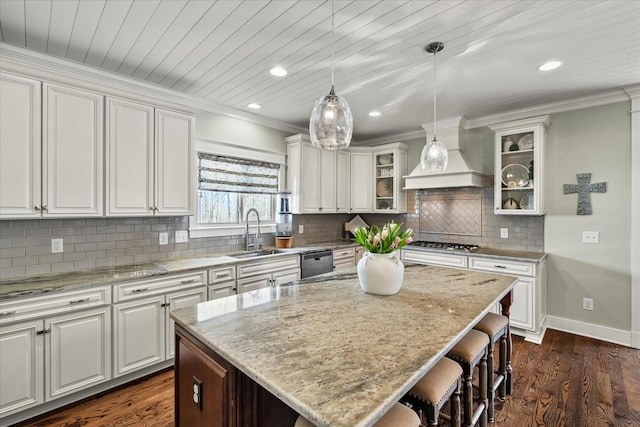 kitchen featuring appliances with stainless steel finishes, a kitchen island, white cabinetry, sink, and custom range hood