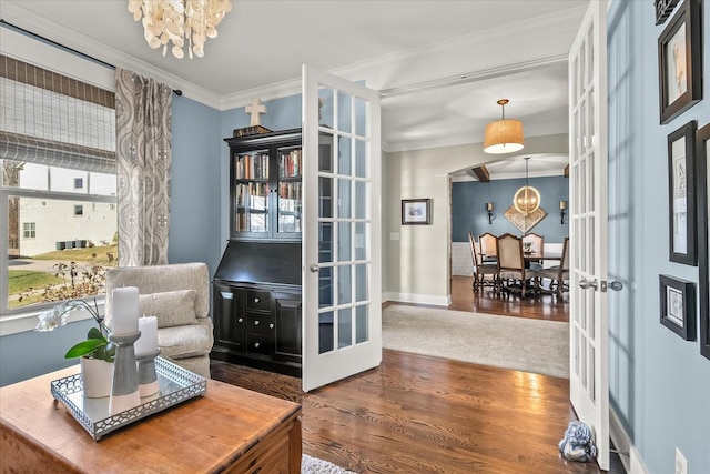 living area with french doors, crown molding, a chandelier, and hardwood / wood-style floors