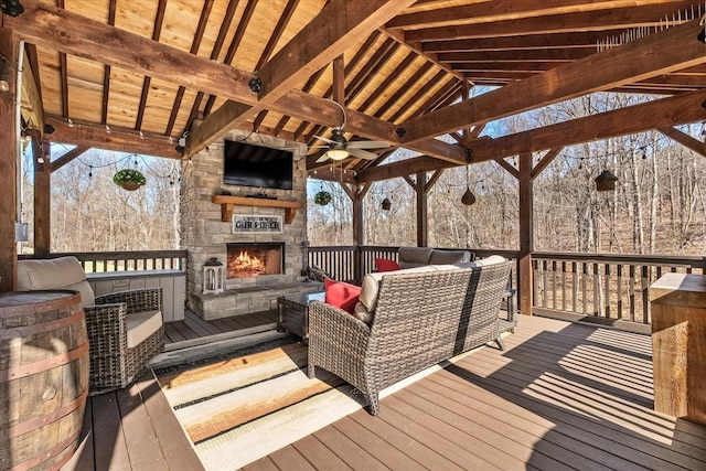 deck with an outdoor living space with a fireplace and ceiling fan