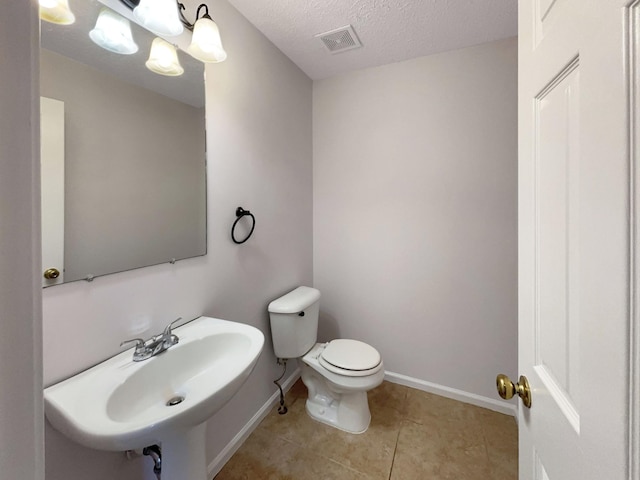 bathroom with tile patterned floors, toilet, sink, and a textured ceiling