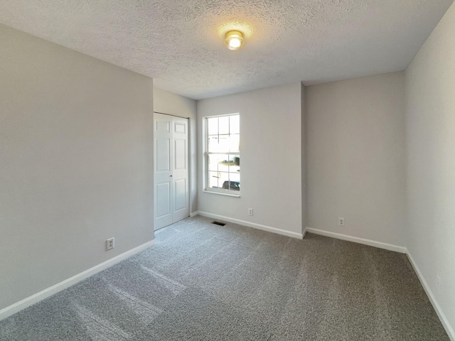 carpeted empty room featuring a textured ceiling