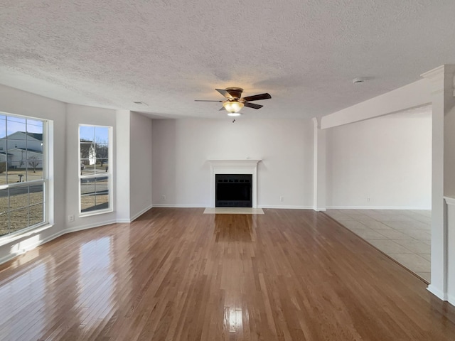 unfurnished living room with hardwood / wood-style flooring, ceiling fan, and a textured ceiling