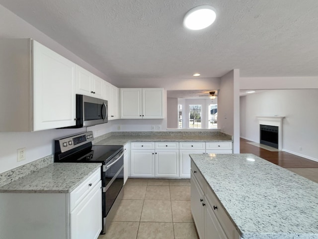 kitchen featuring light stone counters, light tile patterned floors, stainless steel appliances, and white cabinets