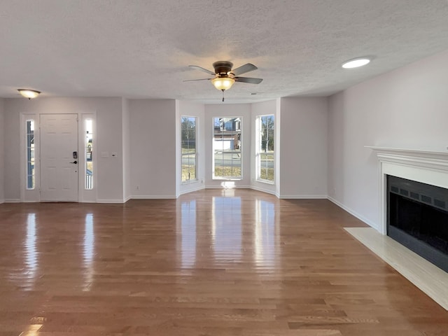 unfurnished living room with hardwood / wood-style flooring, ceiling fan, and a textured ceiling