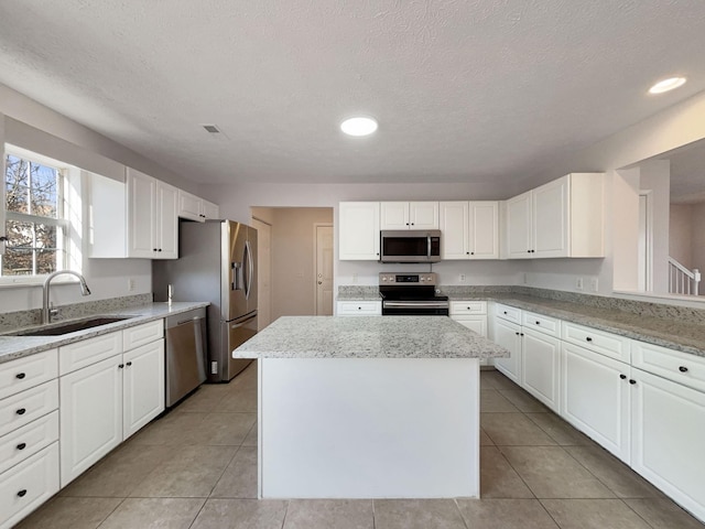 kitchen featuring white cabinetry, appliances with stainless steel finishes, a center island, and sink