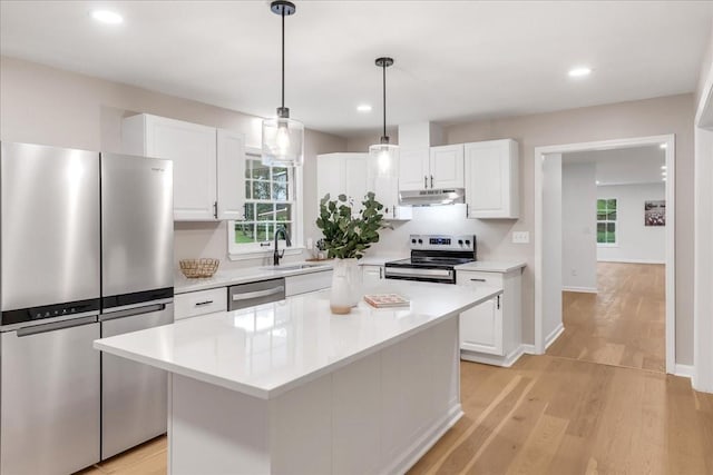 kitchen featuring stainless steel appliances, a center island, light hardwood / wood-style flooring, and white cabinets