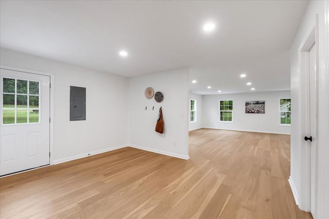 spare room featuring electric panel and light hardwood / wood-style flooring