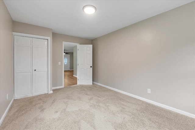 unfurnished bedroom with light colored carpet and a closet