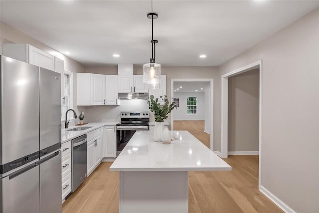 kitchen with sink, appliances with stainless steel finishes, a center island, white cabinets, and decorative light fixtures