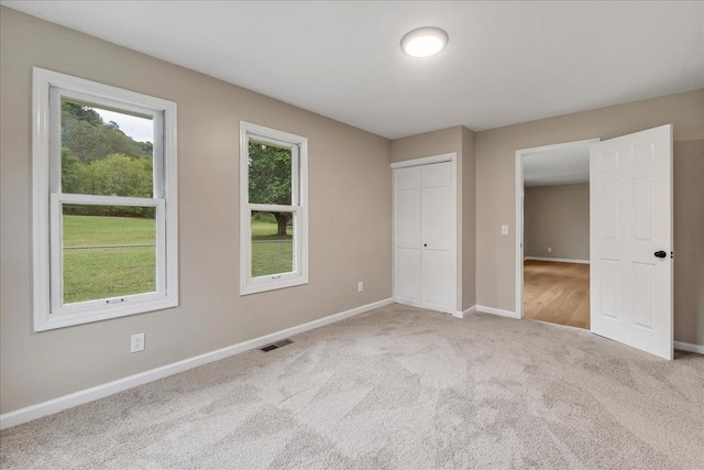 unfurnished bedroom with light colored carpet and a closet