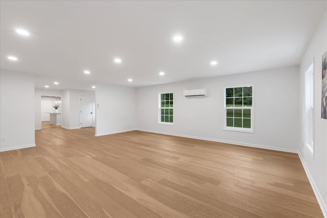 unfurnished living room with light wood-type flooring and a wall unit AC