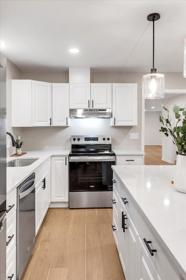 kitchen featuring stainless steel appliances, hanging light fixtures, and white cabinets