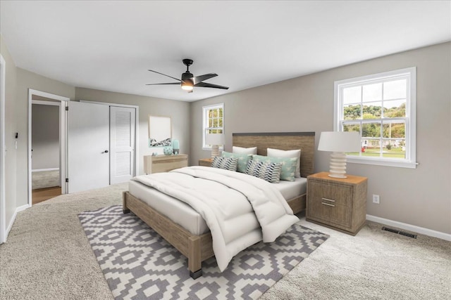 bedroom featuring multiple windows, light colored carpet, ceiling fan, and a closet