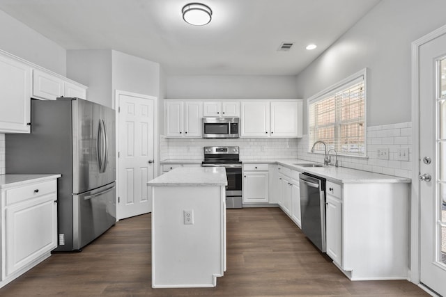 kitchen featuring stainless steel appliances, sink, a kitchen island, and white cabinets