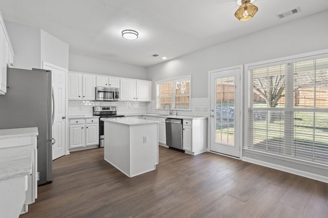 kitchen with plenty of natural light, appliances with stainless steel finishes, a center island, and white cabinets