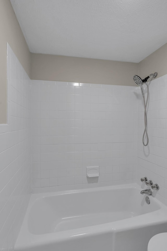 bathroom with shower / tub combination, toilet, and a textured ceiling