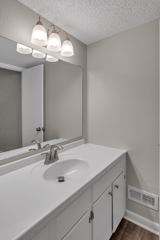 bathroom with vanity, wood-type flooring, and a textured ceiling