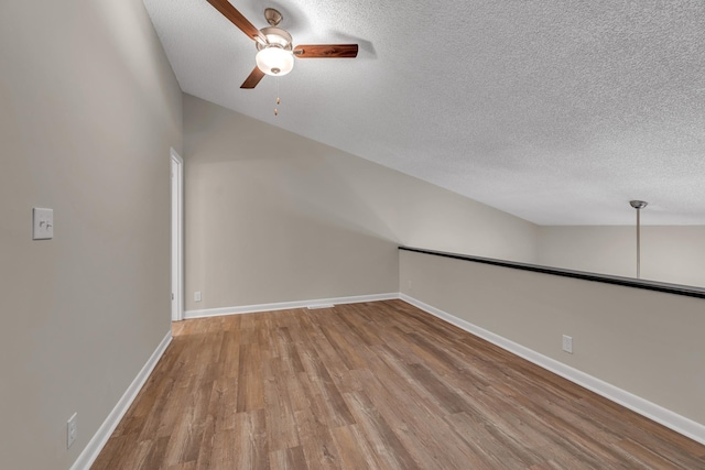 additional living space featuring a textured ceiling, light hardwood / wood-style flooring, ceiling fan, and vaulted ceiling