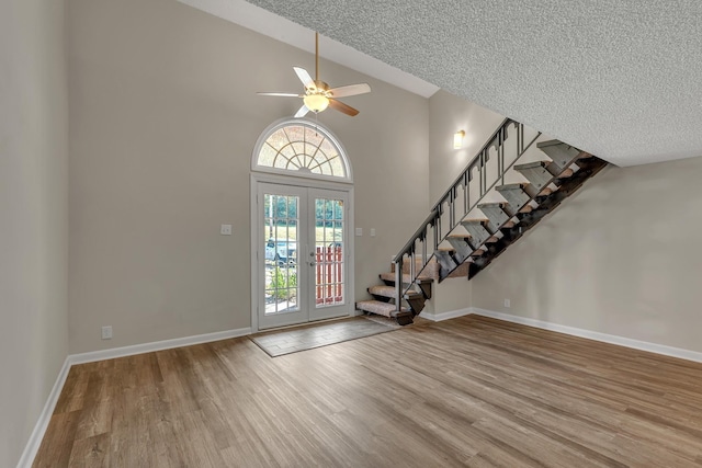 foyer entrance with hardwood / wood-style floors, french doors, ceiling fan, and a high ceiling