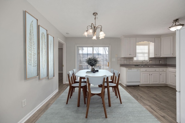 dining space with a healthy amount of sunlight, a chandelier, sink, and light hardwood / wood-style flooring