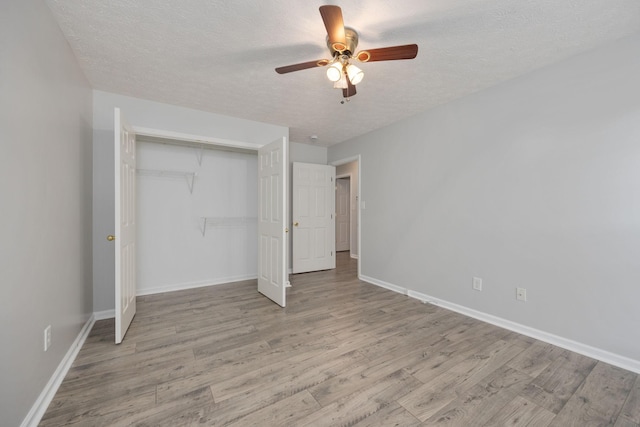 unfurnished bedroom with a textured ceiling, a closet, ceiling fan, and light wood-type flooring