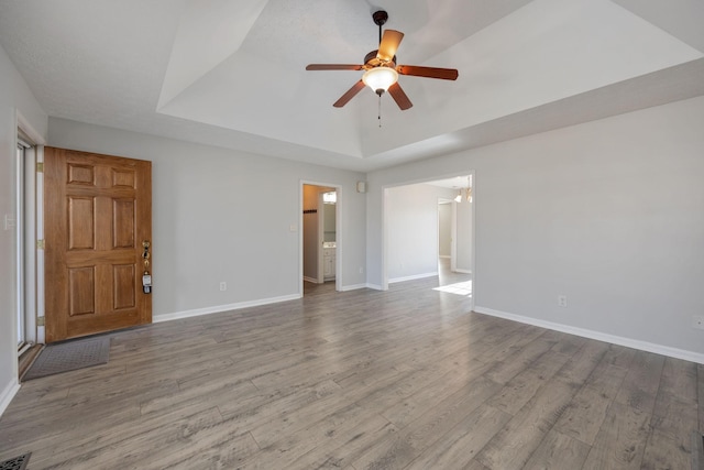 empty room featuring ceiling fan, a raised ceiling, and light hardwood / wood-style flooring